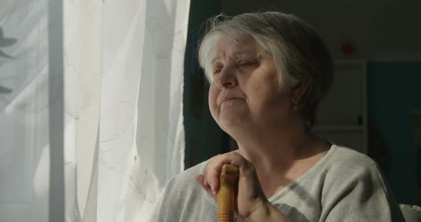 Sitting in Depression Old Woman Looking At The Window Indoors Concept Of Loneliness