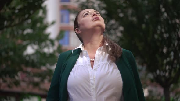 Positive Caucasian Overweight Woman Looking Up Dreaming Standing on Sunny City Street Outdoors