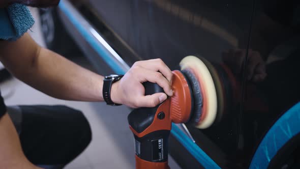 An Experienced Detailing Studio Worker Polishing a Car