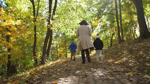 Joyful Mom with Children Running Through Park