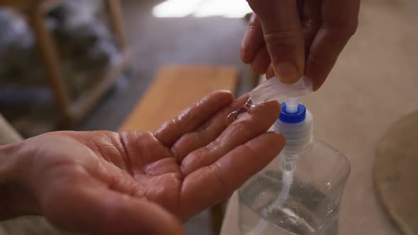 Close up view of potter using hand sanitizer at pottery studio