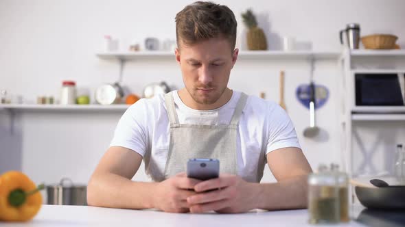 Man in Apron Looking for Culinary Recipe in Internet Kitchen Novice