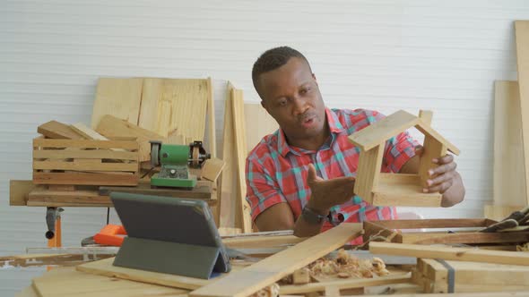 Craftsman constructing wooden home model by learning from online