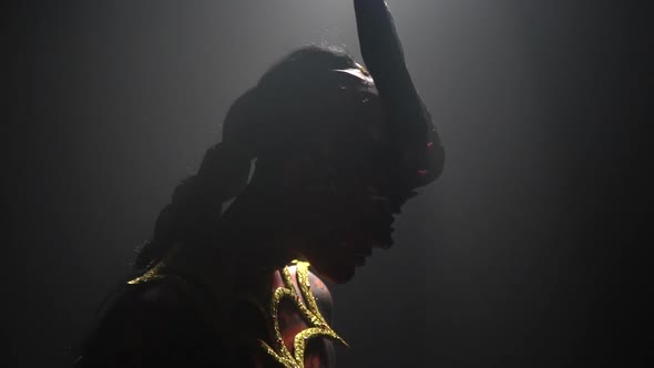 Silhouette of a creepy demon woman with big horns and golden armor