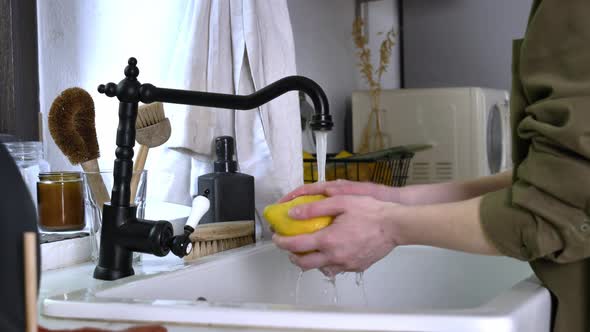 Woman washing lemon under water at kitchen