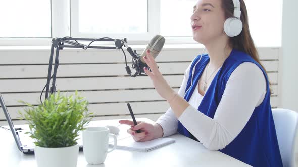 Concept of Streaming and Broadcasting. Young Woman Wearing Headphones and Talking at Online Radio