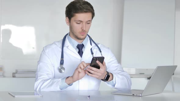 Young Doctor Browsing Smartphone in Clinic