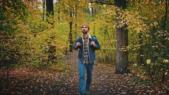 Young Caucasian Man Walking in Autumn Forest with Backpack Slow Motion