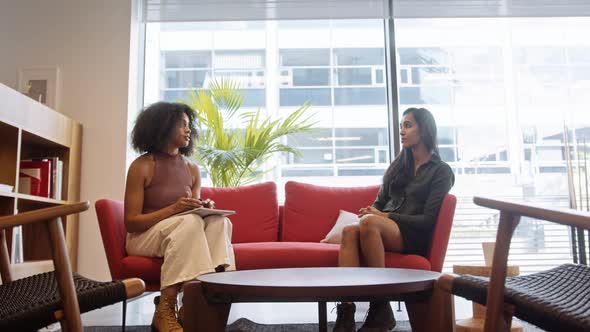 Two Businesswomen Having Informal Socially Distanced Meeting In Office During Health Pandemic