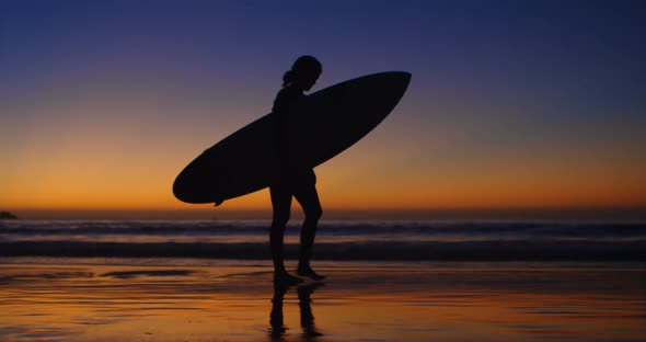 Female surfer walking with surfboard in the beach 