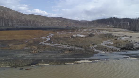 Aerial view of dry riverbed. Cars are driving along the road.