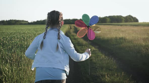 Cheerful Girl Are Running in the Meadow with Wind Turbines As a Sign of Freedom