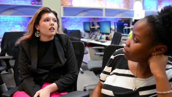 Two young professional women asking and answering questions with each other, biracial