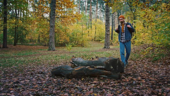 Male Hiker Making Stop at Logs in Forest Taking Thermos From Backpack Rest During Autumn Adventure