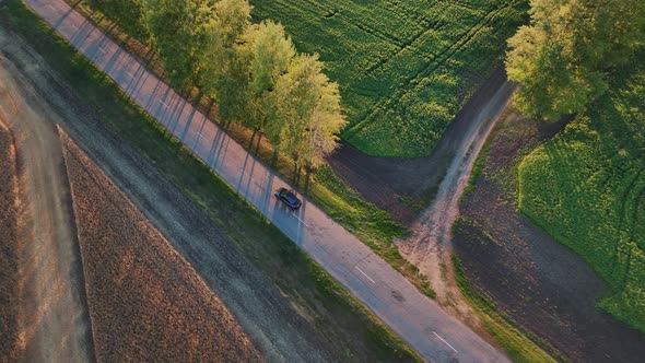 Aerial Footage of a Blue Car Driving Down a Country Road