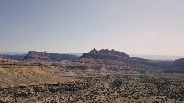 Incredible beautiful drone footage flying down from mesa rock over desert valley, bushes and landsca