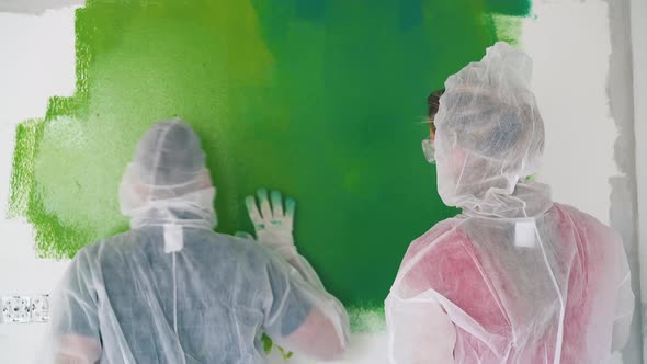 Woman Paints Room Wall Near Dancing Man in Coverall at Home