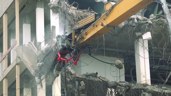 An Arm of a Large Building Machine Tears Part of a Floor Off a Damaged Apartment