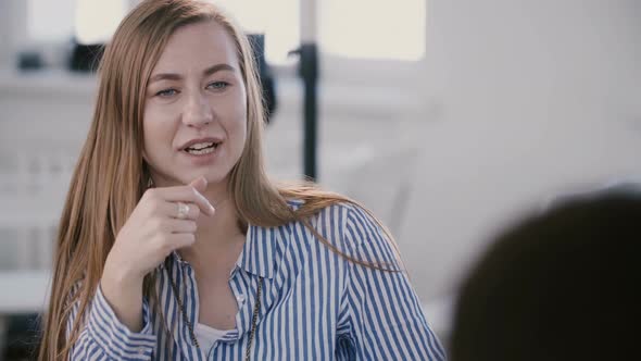 Close-up View of Young Beautiful Successful Caucasian Female Boss Discussing Work with Team at Light