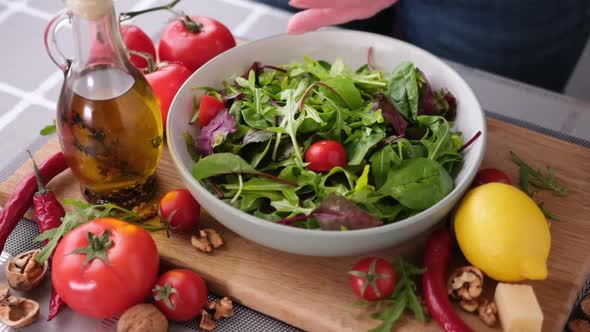 Cherry Tomatoes Falling Into Glass Bowl Full of Arugula Salad Leaves