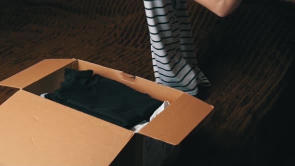 Young Girl Collects a Parcel With Things and Examines Clothes