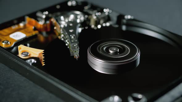 Opened Hard Disk Drive with Spinning Platter. Move of Writing Magnetic Head