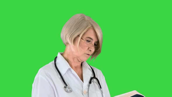 Mature Woman Doctor with a Stethoscope Reading Log on a Green Screen Chroma Key