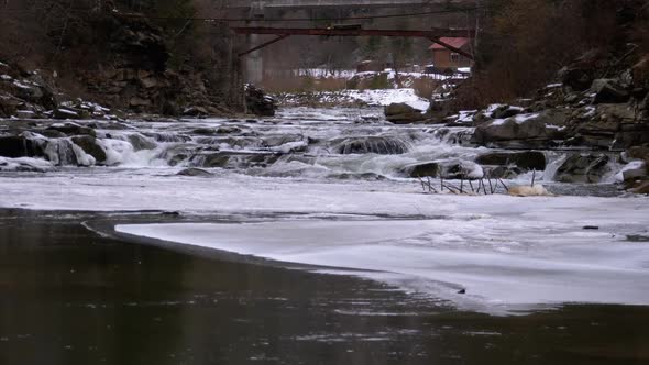 Rapid Flow of Water From a Mountain Creek and Stone Rapids with Snow in Winter. Waterfall. Slow