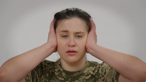 Closeup Portrait of Terrified Military Woman Looking at Camera Closing Ears with Hands