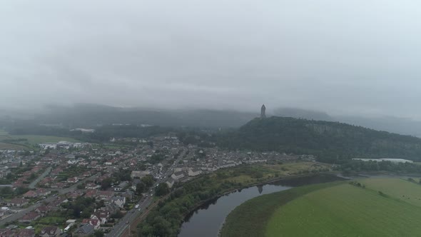 Aerial shot of Stirling over the river forth pulling away from the Wallace Monument on a misty day