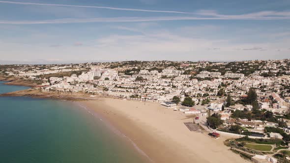 Peaceful Algarve beach, calm emerald ocean and Praia da Luz white townhouses. Aerial scenic view