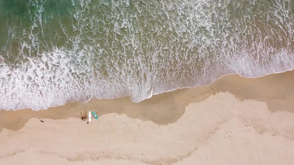 Aerial View of Surf Waves Brushing and Breaking on the White Sandy Seashore on a Summer Day