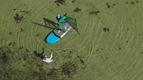 Aerial Drone Footage of Windsurf Instructor Teaching Woman Beginner To Standing on Surfboard