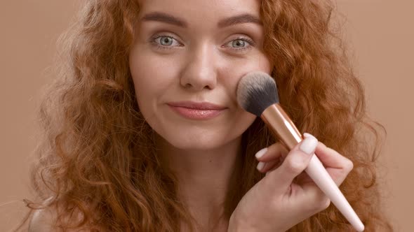 Woman Making Makeup Applying Powder With Cosmetic Brush Beige Background