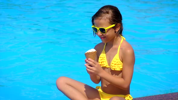 The Child Eats Ice Cream Near the Pool