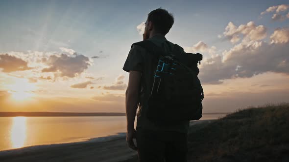 Young Man Photographer with Backpack and Tripod in It