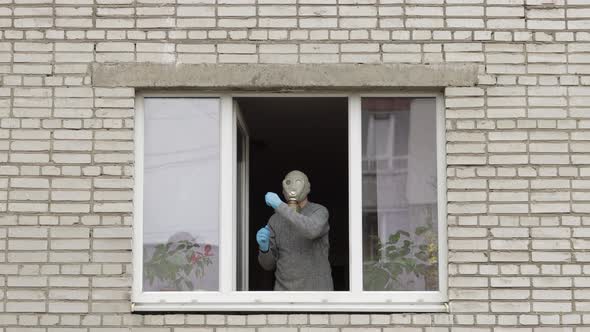 Old Man in Gas Mask Dance at Window Isolated at Home on Quarantine. Coronavirus