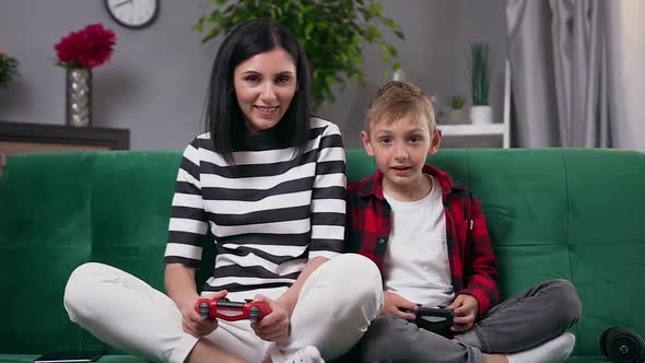 Mother and Son Playing Video Game Applying Gamepads and Having Fun Together