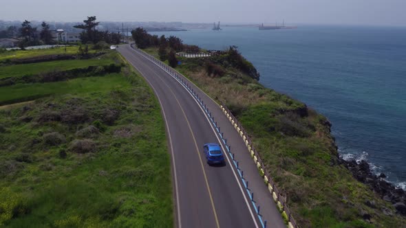 Blue Car Driving along Coastal Road