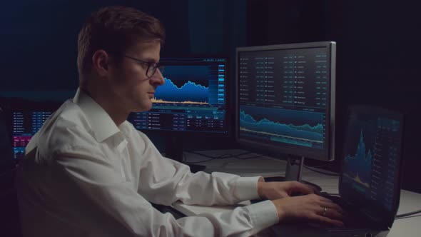 Trader working in office at night using workstation and analysis technology.