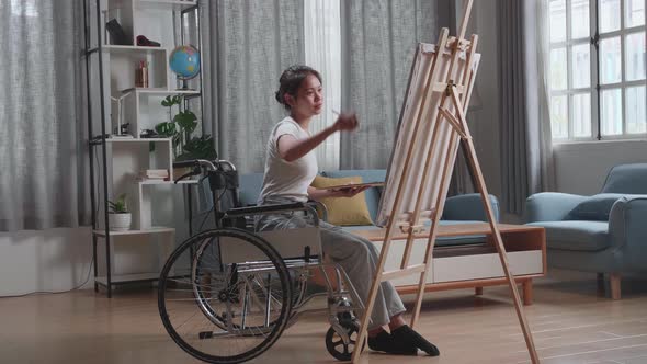 Talented Female Artist Sitting On Wheelchair Using Paint Brush She Creates With Oil Painting