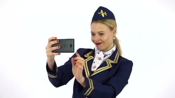 A Young Beautiful Stewardess Takes Pictures with a Smartphone - White Screen Studio