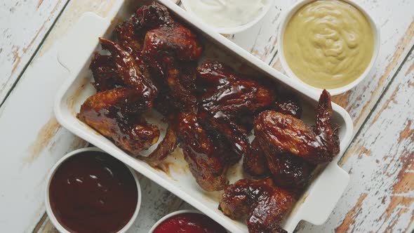 Chicken Wings in Thick Barbecue Sauce with Various Side Dips. Served on White Cast Iron Dish