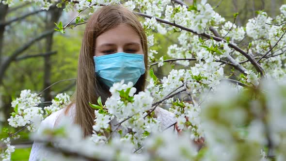 Girl in Medical Mask in Apple Blossoms in Spring