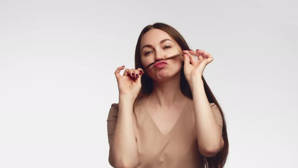 Cute Lovely Young Woman Making Moustache with Her Hair Over White Background