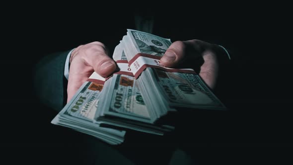 Three Stacks of 10000 American Dollars Bundles in Male Hands on Black Background