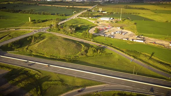 Aerial shot of a busy highway surrounded by large green fields.