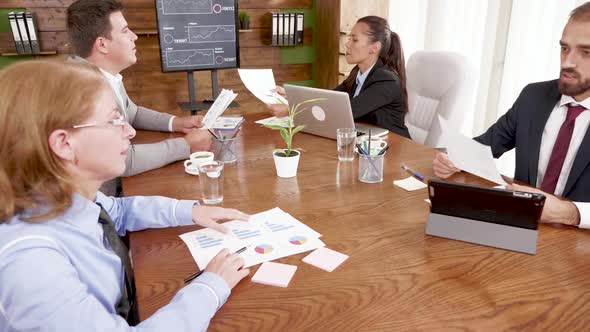 Colleagues Passing Charts To Each Other in the Conference Room