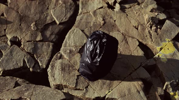 Black Trash Bag Lay on a Rocky Beach