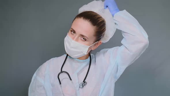 Exhausted Doctor in Protective Coat Takes Off Mask and Cap